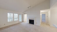 This single-floor, 2-bedroom, 2-bathroom residence offers a thoughtfully arranged layout designed for comfortable everyday living. The spacious living room serves as the centerpiece of the home, featuring vaulted ceilings, plush carpeting, and a tile-surround fireplace that adds warmth and character. Large grid-pane windows and a glass-paneled door bathe the space in natural light while providing access to a private balcony with outdoor views. Track lighting overhead adds a functional, modern touch. The kitchen is efficiently designed with warm wood cabinetry, white countertops, a peninsula with a sink, tile flooring, and a full suite of stainless steel appliances including a gas range, over-the-range microwave, and refrigerator. A pass-through opening connects the kitchen to the living area, enhancing the open feel. Both bedrooms are carpeted and well-lit, with the primary bedroom offering generous proportions and the second bedroom featuring a window with natural light. The two full bathrooms are finished with white tile tub-shower surrounds, vanities with wood cabinetry, and tile flooring. A hallway and closet complete the practical layout of this inviting home.