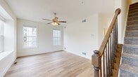 Located at 337 H St in Carlisle, PA, this well-appointed three-story home offers five bedrooms, three full bathrooms, and a thoughtfully organized layout across each level. The ground floor houses the garage — equipped with an automatic opener and electrical panel — alongside entryway hallways that lead into the main living areas. The kitchen is a standout, featuring gray shaker-style cabinetry, granite countertops, stainless steel appliances, pendant lighting, and light hardwood flooring that continues throughout the main living areas. A glass door in the kitchen opens to the exterior, filling the space with natural light. The living room is bright and airy, with large windows, a ceiling fan, and the same warm hardwood flooring. Carpeted bedrooms are found on the upper floors, each with ceiling fans and ample closet space. The primary bedroom enjoys views of lush greenery through a large window. The bathrooms are clean and functional, featuring tub-shower combinations with white surrounds and granite-topped vanities. A dedicated laundry room and pantry add everyday convenience, while two staircases with dark wood railings and carpet treads connect the floors. The home presents a clean, neutral palette throughout, creating a bright and move-in-ready atmosphere.