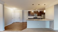 Located at 4890 Edwards Farm Rd in Hilliard, Ohio, this single-floor residence offers a thoughtfully designed layout with modern finishes throughout. The kitchen serves as a standout feature, showcasing rich dark-stained cabinetry, light granite countertops, and a full suite of stainless steel appliances including an electric range, built-in microwave, and refrigerator. A peninsula with an undermount sink and pendant lighting above creates a natural transition into the adjacent living area, which features warm hardwood-style flooring and crown molding details. The bedrooms are carpeted for comfort and filled with natural light from large windows with blinds. The primary bedroom includes a walk-in closet and direct access to an en-suite bathroom featuring a dual-sink granite vanity and a glass-enclosed shower with tile surround. A second bathroom offers a single granite vanity and a tub-shower combination. A dedicated in-unit laundry room with a full-size washer and dryer adds everyday convenience. Neutral tones, clean lines, and consistent finishes throughout give the space a cohesive, move-in-ready feel.