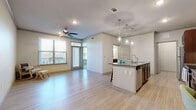 This thoughtfully laid-out 1-bedroom, 1-bathroom residence offers a comfortable and modern living experience across a single floor. The open-concept kitchen and living area serves as the heart of the home, featuring light wood-style flooring that flows seamlessly throughout the main space. A ceiling fan overhead and large windows with abundant natural light create an airy, welcoming atmosphere, while a glass-panel door provides access to the outdoors.

The kitchen is equipped with rich dark wood cabinetry, granite countertops, and a full suite of stainless steel appliances, including a refrigerator, range, and microwave. A peninsula island with pendant lighting offers additional prep space and casual seating. A built-in desk nook adjacent to the kitchen provides a convenient workspace.

The bedroom is carpeted for comfort, features a ceiling fan, and is brightened by a window with outdoor views. It connects directly to a walk-in closet outfitted with multi-level wire shelving and hanging rods for ample storage. The bathroom includes a double vanity with granite countertops, dark wood cabinetry, dual mirrors, and tile flooring.

Completing the unit is a dedicated laundry area with a full-size washer and dryer, adding exceptional everyday convenience to this well-appointed residence.