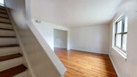 Located at 196 Woodland Dr in Hartford, CT, this two-floor residence offers a practical and straightforward layout spread across two levels. The main floor is the larger of the two and accommodates two living areas, a kitchen, and an entryway. The front living area greets residents with polished hardwood floors, white walls, and a window that draws in natural light with views of the surrounding neighborhood. A staircase leads upward, clearly visible from the main living space and adding a sense of vertical dimension to the home. The second living area connects seamlessly, maintaining the same warm hardwood flooring and clean, neutral palette throughout.

The kitchen features warm wood cabinetry with arched upper door panels, dark laminate countertops, a double basin sink positioned beneath a window, and tile flooring that contrasts with the hardwood found elsewhere.

Upstairs, the bedroom is a well-proportioned space with hardwood floors, multiple windows providing ample natural light, and two closets offering practical storage. The full bathroom retains a retro character, highlighted by pink wall tiles accented with black trim, a wall-mounted sink, a bathtub, and a window for ventilation.