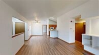 This single-floor residence offers a thoughtfully designed layout that balances open communal spaces with comfortable private retreats. The living area is anchored by light wood-look flooring, a ceiling fan, and a built-in shelving unit with recessed lighting, providing both functionality and a focal point for the room. A half-wall partition connects the living space to the kitchen, creating an open-concept feel while maintaining subtle definition between areas.

The galley-style kitchen is well-equipped with warm honey-toned wood cabinetry, white appliances including a range, microwave, and refrigerator, and a peninsula with a sink and countertop overhang ideal for casual dining. Vaulted ceilings above the kitchen lend a sense of added height and airiness to the space.

The bedrooms feature plush carpeting and crisp white walls. One bedroom benefits from vaulted ceilings and a window with natural light, while another offers a standard ceiling with a window overlooking greenery outside.

Two bathrooms serve the residence. One includes a walk-in shower stall, a single-sink vanity with warm wood cabinetry, a large mirror, and tile flooring. The second features a full tub-shower combo and a granite-topped vanity, offering a more classic bathroom arrangement. Throughout the home, wood-toned trim and doors provide a cohesive, warm aesthetic.