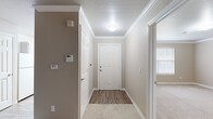 This single-story, 3-bedroom, 2-bathroom home is thoughtfully laid out to maximize functionality and comfort. The entrance greets you with a classic six-panel white door, elegant crown molding, and warm neutral-toned walls that carry throughout the entire home, creating a cohesive and inviting atmosphere.

The interior transitions seamlessly between wood-look vinyl flooring in the main thoroughfares and plush carpeting in the living and bedroom areas. Crown molding is a consistent architectural detail found throughout, adding a refined touch to each room. The galley-style kitchen features white cabinetry, white appliances including a full-size refrigerator and range, and durable countertops, with an open sightline toward the main living area.

The generously sized primary bedroom offers ample room to accommodate large furnishings, while the bathrooms are finished with wide vanities, wood-look vinyl flooring, and accessibility-friendly grab bars in the shower and bath area. Closet space is well-represented, including a spacious walk-in closet fitted with wire shelving for organized storage.

A dedicated laundry room accommodates a full-size side-by-side washer and dryer. The secondary bedrooms are comfortable and bright, each featuring carpet and crown molding. The home's neutral palette and clean finishes make it a versatile and move-in-ready space.