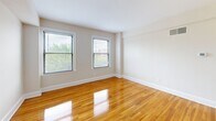 Located at 1629 Columbia Rd NW in Washington, DC's vibrant Columbia Heights neighborhood, this efficient single-floor unit offers a thoughtfully organized layout comprising a living room, a dedicated closet, and a full bathroom. The living room is a bright, inviting space highlighted by warm, polished hardwood floors that run throughout, neutral cream-toned walls, and crisp white baseboards that lend a clean, classic aesthetic. Multiple windows allow generous natural light to fill the room while offering pleasant views of the surrounding greenery, creating an open and airy atmosphere despite the intimate footprint. The walk-in closet provides practical storage with wire shelving units and hanging rods along the walls, maximizing organization, and continues the same hardwood flooring for a cohesive feel. The bathroom features a tiled tub-shower surround with white subway-style tiles and a window that introduces natural light, maintaining a bright and clean environment. The overall design of the unit is simple and timeless, with consistent finishes and neutral tones throughout that provide a versatile canvas for personalization. Its location in Columbia Heights places it within easy reach of the neighborhood's diverse dining, shopping, and transit options.