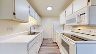 This single-floor residence in Howell, Michigan offers a well-organized layout comprising one bedroom and one bathroom. The living area is generously sized, featuring plush wall-to-wall carpeting, neutral cream-toned walls, and multiple diamond-pane windows that invite abundant natural light and outdoor views of the surrounding greenery. A ceiling fan adds both comfort and functionality to the space.

The galley-style kitchen is efficiently designed with white cabinetry lining both sides, providing ample storage. It includes wood-look flooring, a stainless steel sink, white appliances — including a refrigerator, range with oven, microwave, and dishwasher — and overhead lighting.

The bedroom continues the carpeted flooring and neutral palette found throughout the home. It features a diamond-pane window, a bifold-door closet with built-in shelving, and a dedicated vanity or utility nook, offering practical storage solutions.

The bathroom is clean and functional, featuring a full tub-shower combination with tiled surround, a toilet, and wood-look flooring that ties into the kitchen aesthetic.

Overall, the space maintains a bright, neutral, and cohesive design throughout, making it a versatile and move-in-ready residence located in Howell, MI.