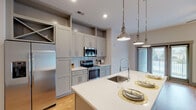 Located at 900 Hobbs Rd in Greensboro, NC, this single-floor residence presents a thoughtfully designed layout with modern finishes throughout. The open-concept kitchen serves as the heart of the home, showcasing gray shaker-style cabinetry, white quartz countertops, a subway tile backsplash, and a full suite of stainless steel appliances. A generously sized center island with an undermount sink and pendant lighting overhead makes this space equally functional and visually appealing. Warm hardwood flooring extends through the kitchen and living area, creating a bright and cohesive atmosphere enhanced by recessed lighting and natural light from large windows with blinds. The bedrooms feature soft carpeting and neutral tones, offering a calm retreat. One bedroom includes a walk-in closet outfitted with wire shelving for ample storage, while another benefits from a large window overlooking the surrounding greenery. The bathrooms are finished with tile flooring and gray cabinetry. One features a sleek frameless glass walk-in shower with subway tile surround, while another includes a full tub-shower combination. Panel-style interior doors and consistent gray trim detail unify the design aesthetic across the entire space.