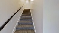 This contemporary townhouse in South Ogden, Utah, offers a well-designed living space across three floors, totaling 1220 square feet. The property features three bedrooms and three bathrooms, including a spacious primary bedroom of 160 square feet. The ground floor houses a 70 square foot garage, while the first and second floors comprise 560 and 580 square feet respectively.

The interior showcases a modern aesthetic with an open-concept design. The kitchen and living area blend seamlessly, featuring crisp white cabinetry, stainless steel appliances, and a central island. The kitchen's subway tile backsplash and quartz countertops add a touch of elegance. Throughout the home, recessed lighting and large windows provide ample natural light, enhancing the sense of space.

Flooring varies between rooms, with stylish wood-look laminate in the main living areas and plush carpeting in the bedrooms. The bathrooms are outfitted with contemporary fixtures, including sleek vanities and modern tiled showers. Multiple staircases connect the three levels, creating an efficient flow throughout the home.

The property's exterior is complemented by manicured landscaping, visible through the large windows that offer views of the surrounding neighborhood. With its combination of style, space, and functionality, this townhouse presents an attractive option for modern living in South Ogden.