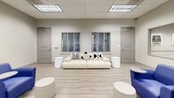 This 870 square foot office space in Riverside, CA, offers a contemporary and functional environment. The open-plan layout features a harmonious blend of work and relaxation areas. Vibrant blue armchairs with attached tables provide comfortable seating, while white ottomans offer flexible additional seating options. The space is brightened by fluorescent lighting and adorned with modern artwork, including abstract paintings and typewriter prints, adding visual interest to the neutral walls. A dedicated meeting area showcases a solid wood table with sleek office chairs, ideal for collaborative work. The room also includes a stylish white couch, perfect for casual conversations or brief respites. Storage needs are met with white modular shelving units, which also display decorative plants, enhancing the space's aesthetic appeal. Large interior windows and multiple doors suggest connectivity to adjacent areas, promoting an open and accessible work environment. The light wood-look flooring throughout contributes to the space's bright and airy atmosphere, creating a professional yet inviting office setting.