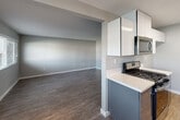 Located at 120 S Grand Ave in Anaheim, California, this single-floor residence offers a thoughtfully updated interior with a clean, modern aesthetic throughout. The galley-style kitchen is a standout feature, showcasing two-tone cabinetry with crisp white upper cabinets and slate-blue lower cabinets, complemented by bright white countertops and stainless steel appliances, including a gas range, built-in microwave, dishwasher, and refrigerator. Light wood-style flooring and recessed overhead lighting complete the kitchen's contemporary look. The open living and dining areas are finished with durable wood-style flooring in a warm tone, neutral gray walls, and textured ceilings. Multiple windows allow natural light to flow throughout, while a ceiling fan adds both style and function. A sliding glass door fitted with vertical blinds opens to an outdoor area, bringing in additional light and providing convenient exterior access. The bedroom is a well-proportioned, quiet space with matching flooring and soft neutral tones. The bathroom is clean and functional, featuring a tub-shower combination with tile surround, a single vanity with a large mirror, and brushed nickel fixtures. Overall, the space presents a fresh, move-in-ready environment with modern updates and a cohesive design palette.