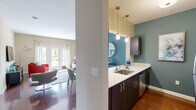 This well-appointed one-bedroom, one-bathroom unit at 12 Valley St in Everett, MA offers a thoughtfully designed open-concept layout across a single floor. The living room is a bright and welcoming space, anchored by a bold teal accent wall and French doors that open to a private balcony with outdoor views, allowing abundant natural light to fill the room. Rich hardwood flooring runs throughout the main living areas, adding warmth and continuity.

The kitchen features dark espresso cabinetry, sleek white countertops, stainless steel appliances including a full-size refrigerator, and stylish pendant lighting overhead. A pass-through window connects the kitchen to the dining area, creating an interactive and sociable layout ideal for entertaining. The dining space comfortably accommodates a full table and chairs.

The bedroom is a generously sized retreat with plush carpet, a large double-door closet, and multiple windows that invite natural light and outdoor views. A teal accent wall adds a cohesive design element that ties the space together.

The bathroom is finished with large-format tile flooring, a dark vanity with a clean white countertop, and a well-lit mirror above the sink, offering a polished and functional design. Overall, this unit presents a modern, cohesive aesthetic with vibrant accent colors and quality finishes throughout.