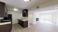 Located at 21021 Vanowen St in Canoga Park, California, this single-floor residence offers a clean, contemporary design with a neutral color palette and modern finishes throughout. The galley-style kitchen is a standout feature, outfitted with rich dark espresso cabinetry, light quartz countertops, a stainless steel gas range, microwave, refrigerator, and a double-basin sink — all complemented by luxury vinyl plank flooring that extends throughout the main living areas. The kitchen opens into a dining area, which flows seamlessly into a bright, spacious living room. The living room benefits from abundant natural light streaming through large sliding glass doors fitted with vertical blinds, and features a fireplace, making it an inviting focal point of the home. A hallway leads to the private areas of the residence, including bedrooms finished with plush carpeting for added comfort. Two bathrooms are present — one featuring a full tub and shower combo with sliding glass doors and a dark-cabinetry vanity, and a second with a window for natural light, a matching vanity, and clean, simple finishes. Throughout the space, recessed lighting and flush-mount fixtures provide consistent illumination, while the cohesive design creates a modern and comfortable living environment.