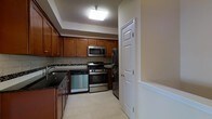 This two-floor residence offers a thoughtfully designed layout spread across two levels, combining functionality with classic detailing throughout. The kitchen serves as a standout feature, showcasing warm honey-toned wood cabinetry that extends to the ceiling, providing generous storage space. Dark granite countertops offer a striking contrast against the cabinetry, while a tiled backsplash adds a refined finishing touch. The kitchen is fully equipped with a suite of stainless steel appliances, including a gas range, built-in microwave, dishwasher, and refrigerator, making it well-suited for everyday cooking and entertaining alike. Light tile flooring runs underfoot, contributing to a clean and bright aesthetic, complemented by recessed ceiling lighting that illuminates the workspace effectively. A paneled interior door leads from the kitchen, hinting at the additional rooms and spaces that make up the broader floor plan across both levels. The overall ambiance of the space is practical yet polished, with consistent finishes and quality materials that lend a sense of cohesion throughout. With two floors to explore, the residence provides ample room for comfortable day-to-day living.