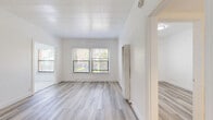 Located at 1227 S Central Ave in Glendale, CA, this 2-bedroom, 1-bathroom unit offers a thoughtfully designed single-floor layout with clean, modern finishes throughout. Light wood-style luxury vinyl flooring runs through the living areas and bedrooms, complementing the crisp white walls and creating a bright, cohesive aesthetic.

The spacious primary bedroom is the largest room in the unit, featuring multiple windows with garden views, a textured shiplap-style ceiling, a built-in wall heater, and direct access to a well-appointed closet with built-in cabinetry and drawers. The second bedroom is equally bright, with a window overlooking lush greenery, white walls, and the same light flooring.

The kitchen stands out with its contemporary renovation, showcasing white shaker cabinets with matte black hardware, marble-look quartz countertops, a large undermount sink with a black pull-down faucet, polished marble-tile flooring, and stainless steel appliances including a gas range and microwave. The bathroom maintains the clean design language with marble-tile flooring, a pedestal sink with a black faucet, a full bathtub, and a wall-mounted mirror. Natural light flows throughout the unit, enhancing its fresh and inviting atmosphere.