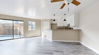 Located in the vibrant West Hollywood neighborhood of Los Angeles, this one-bedroom, one-bathroom unit offers a well-designed open-concept layout finished with light gray wood-style flooring throughout. The combined kitchen and living area forms the heart of the space, where a peninsula with granite countertops and dual pendant lighting serves as both a workspace and casual dining spot. White shaker cabinetry, a stainless steel range, and a modern faucet complete the kitchen's clean, functional aesthetic. A wood-blade ceiling fan anchors the living area, and a sliding glass door opens directly to a private fenced outdoor patio, filling the room with natural light. A second window reinforces the bright, airy feel of the living space. The bedroom is a comfortable retreat featuring a wall-mounted split AC unit, full-width mirrored closet doors, and its own sliding glass door that provides additional outdoor access and natural light. The bathroom is finished with the same granite countertop found in the kitchen, a vessel-style sink set in white cabinetry, and a full tub-shower combination. Neutral warm-beige walls and consistent flooring create a cohesive, modern feel throughout this efficiently designed Los Angeles residence.