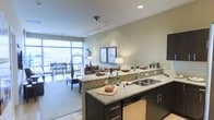 Located at 777 S Broad Street in the heart of Philadelphia, this single-floor residence offers a thoughtfully designed open-concept layout that seamlessly blends the kitchen, dining, and living areas into one cohesive living space. The kitchen is a standout feature, showcasing granite countertops, dark espresso cabinetry, a stainless steel sink, and a dishwasher — all centered around a generous island that serves as both a prep space and a casual gathering spot. The living and dining areas are bathed in natural light, courtesy of expansive floor-to-ceiling windows that frame sweeping views of the Philadelphia skyline. These large windows create an airy, open ambiance throughout the space. Track lighting and recessed fixtures provide warm, adjustable illumination to complement the natural light. The living area transitions smoothly to what appears to be a private outdoor balcony, further enhancing the connection between interior and exterior. Neutral wall tones and carpet flooring in the living area contribute to a calm, inviting atmosphere. The overall design reflects a contemporary urban aesthetic, combining functional elegance with comfortable everyday living in one of Philadelphia's most vibrant corridors.