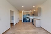 Located at 14455 East Ellsworth Avenue in Aurora, Colorado, this two-bedroom, two-bathroom residence offers a well-designed single-floor layout with a clean, contemporary aesthetic throughout. Light-toned wood-look flooring runs continuously through the space, complementing the crisp white walls and creating a bright, cohesive atmosphere.

The open-concept living, dining, and kitchen area serves as the heart of the home. The kitchen is equipped with modern light wood cabinetry, granite-style countertops, and a full suite of black appliances including a refrigerator, range, built-in microwave, and dishwasher — providing both functionality and style.

A hallway connects the main living area to the private quarters, where two bedrooms offer comfortable accommodations. The primary bedroom is a well-proportioned retreat, while the second bedroom features a sliding-door closet and a ceiling fan. Both rooms are finished with the same warm wood-look flooring and neutral walls, allowing for flexible furnishing options.

Each of the two full bathrooms is outfitted with a tub/shower combination, a vanity with granite-style countertops, and matching wood-look flooring, maintaining a consistent design language throughout. Additional features include dedicated closet spaces, a laundry area, and recessed lighting in the kitchen, contributing to the home's practical and polished feel.