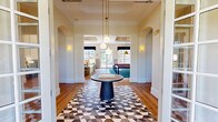 Located at 151 N Main St in Bellingham, Massachusetts, this generously sized single-floor amenity center offers a wide array of spaces designed for recreation, wellness, and community engagement. The welcoming lobby greets visitors with a striking marble-topped reception desk, a coffered tray ceiling, wainscoting panels, and warm hardwood flooring, establishing an immediately polished and professional atmosphere. Adjacent to the entry is a cozy lounge nook featuring a coffee station, a bold diagonal shiplap accent wall in deep teal, and stylish bubble chairs, creating an inviting retreat. The dedicated workspace includes large windows that bathe the room in natural light, a dramatic marble accent wall, and workstation desks paired with a central conference table. The fitness center is comprehensively equipped with a full suite of strength and cardio machines, floor-to-ceiling mirrors, and a chevron-patterned carpet. Entertainment options abound: a billiards lounge features a vibrant blue pool table beneath a brass pendant light with crown molding details, while a private theater room offers leather recliner seating, a projector, and plush draping. Two dedicated game rooms provide ping-pong, arcade cabinets, pinball machines, and racing simulators. Well-connected hallways with vending amenities complete this dynamic facility.
