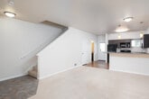 Located at 980 Ross Ave in DuPont, Washington, this two-story residence offers a thoughtfully designed layout spread across two levels. The main floor welcomes you with a tiled entryway that transitions into a generous carpeted living area, which flows openly into the kitchen. The kitchen is well-equipped with rich dark-brown cabinetry, ample countertop space, a breakfast bar peninsula, hardwood-style flooring, and black appliances including a range, microwave, and dishwasher — all illuminated by warm pendant lighting. A staircase with a clean white railing connects the main level to the upper floor, where carpeted bedrooms offer a comfortable retreat. The bedrooms are bright and airy, benefiting from multiple windows dressed with blinds that frame views of the surrounding neighborhood and greenery. The bathrooms feature dark wood vanities with generous counter space and large mirrors that enhance the sense of space. Neutral warm tones are carried throughout the home, creating a cohesive and inviting atmosphere. The combination of functional design, natural light, and quality finishes makes this DuPont residence a practical and comfortable living space.
