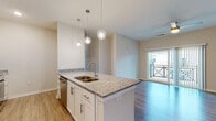 Located at 719 Lantern Walk Dr in Little River, South Carolina, this single-floor residence offers a well-designed, contemporary layout with quality finishes throughout. The kitchen serves as a central highlight, featuring a granite-topped island with a double undermount sink, pendant lighting, white shaker cabinetry with brushed nickel hardware, a subway tile backsplash, and a full suite of stainless steel appliances including a refrigerator, range, microwave, and dishwasher. Light wood-look flooring flows through the kitchen and living areas, creating a cohesive and easy-to-maintain foundation. The open living area is bright and airy, benefiting from natural light and sliding glass doors that lead to a private balcony. The bedrooms are carpeted for comfort, each featuring ceiling fans, windows with neighborhood views, and ample space. The bathrooms are finished with granite-topped white vanities, wood-look flooring, and tub-shower combinations. A dedicated in-unit laundry room with a full-size front-load washer and dryer adds everyday convenience. The overall aesthetic is clean and modern, with neutral tones and consistent finishes that create a cohesive, move-in-ready environment throughout.
