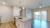 Located at 719 Lantern Walk Dr in Little River, South Carolina, this single-floor residence offers a well-designed, contemporary layout with quality finishes throughout. The kitchen serves as a central highlight, featuring a granite-topped island with a double undermount sink, pendant lighting, white shaker cabinetry with brushed nickel hardware, a subway tile backsplash, and a full suite of stainless steel appliances including a refrigerator, range, microwave, and dishwasher. Light wood-look flooring flows through the kitchen and living areas, creating a cohesive and easy-to-maintain foundation. The open living area is bright and airy, benefiting from natural light and sliding glass doors that lead to a private balcony. The bedrooms are carpeted for comfort, each featuring ceiling fans, windows with neighborhood views, and ample space. The bathrooms are finished with granite-topped white vanities, wood-look flooring, and tub-shower combinations. A dedicated in-unit laundry room with a full-size front-load washer and dryer adds everyday convenience. The overall aesthetic is clean and modern, with neutral tones and consistent finishes that create a cohesive, move-in-ready environment throughout.