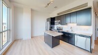 Located at 1150 4th St SW in Washington, DC, this penthouse unit offers a well-designed two-bedroom, two-bathroom layout across a single floor. Light wood flooring runs throughout, complementing the clean, contemporary aesthetic defined by crisp white walls and modern finishes.

The kitchen is a standout feature, equipped with dark cabinetry, stainless steel appliances, a white subway tile backsplash, and a granite-topped island that provides both prep space and casual seating. Track lighting above adds a polished touch.

Both bedrooms benefit from floor-to-ceiling windows that invite abundant natural light and frame views of the surrounding Washington, DC cityscape. The primary bedroom is generously proportioned and includes a ceiling fan, while clerestory-style windows near the ceiling add to the airy atmosphere. Each bedroom includes dedicated closet space.

The two bathrooms are finished with granite-topped vanities, large-format tile flooring, and white subway tile surrounds. One features a soaking tub and shower combination, while the other offers a frameless glass walk-in shower.

A central hallway connects the rooms efficiently, with a sliding barn-style door visible from the entry. The unit's penthouse position provides elevated city views, making it a bright and functional residence in the heart of Southwest DC.