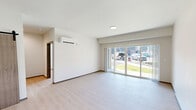 Located at 4415 East Longfellow Avenue in Spokane, WA, this well-appointed one-bedroom, one-bathroom unit offers a thoughtfully designed open-concept layout finished with light wood-style flooring throughout. The kitchen serves as a central highlight, featuring white shaker cabinetry extending to the ceiling, a classic subway tile backsplash, a center island with quartz countertops, stainless steel appliances including a French door refrigerator, gas range, built-in microwave, and dishwasher, and pendant lighting above the island that adds a modern touch. The open living area is bright and airy, benefiting from a sliding glass door that leads to an outdoor patio and provides views of the surrounding greenery. The bedroom is comfortably sized, fitted with a wall-mounted mini-split HVAC system for year-round climate control, and receives natural light through dual windows with blinds. A dedicated walk-in closet with wire shelving offers generous storage space. The bathroom is clean and contemporary, featuring white shaker vanity cabinets, a quartz countertop, a framed mirror, and a full soaking tub with shower combination. The unit's consistent neutral palette and modern finishes create a bright, cohesive living environment throughout.