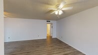 This single-floor unit offers a practical and well-organized layout designed to maximize functionality across its living spaces. The interior is finished with wood-look laminate flooring throughout, providing a cohesive and easy-to-maintain foundation in every room.

The open living and dining area is generously proportioned, featuring a textured ceiling, ceiling fans with integrated lighting, and neutral white walls that lend a clean, bright atmosphere. Windows fitted with horizontal blinds allow for natural light while maintaining privacy. A front entry door opens directly into this shared living space, which connects seamlessly to the kitchen via an open pass-through.

The galley-style kitchen is efficiently arranged with gray lower and upper cabinetry, light granite-pattern countertops, a stainless steel sink, and white appliances including an electric range and refrigerator. A range hood is positioned above the stove, and ample cabinet storage lines both sides of the kitchen corridor.

The bedrooms are well-sized, each equipped with ceiling fans, wood-look flooring, and windows that introduce natural light. The rooms offer a neutral palette with white walls and clean trim throughout.

The bathroom features a white vanity with light countertop, an oval mirror, brushed nickel fixtures, and a lighted vanity bar, creating a tidy and functional space. Overall, the unit presents a straightforward, move-in-ready layout suitable for a range of occupants.