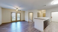 Located in Covington, GA, this single-floor 2-bedroom, 2-bathroom unit offers a practical and comfortable layout with a clean, neutral aesthetic throughout. The open-concept kitchen and living area serves as the heart of the home, featuring wood-look plank flooring, a peninsula island with a marble-style countertop, dark espresso cabinetry, and black appliances including a refrigerator, range, and microwave. A pendant light fixture accents the dining area, while a door leads to a private outdoor balcony, bringing in natural light and outdoor views. The spacious living room area continues the wood-look flooring and is brightened by a ceiling fan and access to the balcony through French-style glass doors. Both bedrooms are carpeted and generously sized, each equipped with ceiling fans and windows that allow natural light to filter in. The expansive primary bedroom includes a dedicated closet. The two bathrooms are finished with wood-look flooring, dark vanity cabinetry, marble-style countertops, and shower/tub combinations. Additional features include a laundry area and two closets, providing ample storage. The unit presents a cohesive, move-in ready environment with consistent finishes throughout.