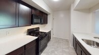 This two-story townhome at Oxford Arms in Edison, NJ offers a well-appointed layout across two floors. The kitchen features dark espresso cabinetry, white countertops, a gas range, and a built-in microwave, all set atop light stone-look tile flooring. Warm hardwood floors flow throughout the main and upper living areas, adding a timeless character to the home.

The living spaces are generously sized and bathed in natural light, with large windows and a sliding glass door opening to a private balcony overlooking lush greenery. The upper level showcases a distinctive vaulted, sloped ceiling that adds architectural interest and a sense of openness to the space.

The three bathrooms are thoughtfully designed, each featuring dark espresso vanities with white countertops and mosaic tile flooring. One bathroom includes a glass-enclosed walk-in shower, while another offers a full soaking tub and shower combination. A third half-bath provides added convenience.

The bedrooms are bright and comfortable, with hardwood floors and windows framing views of the surrounding trees. Throughout the home, a clean, neutral palette creates a fresh and inviting ambiance, making this townhome a well-rounded residence in a convenient Edison location.