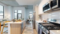 Located in Denver's Golden Triangle neighborhood, this thoughtfully designed 2-bedroom, 2-bathroom residence offers a seamless blend of modern aesthetics and functional living. Light wood flooring and a neutral palette flow throughout, complemented by exposed concrete accents and large black-framed windows that invite abundant natural light and urban views.

The open-concept kitchen is a standout feature, boasting light wood cabinetry, white quartz countertops, a gas range, stainless steel appliances, a tile backsplash, and a central island with bar seating — ideal for both everyday dining and entertaining. The kitchen connects naturally to a dedicated dining area and a bright living room with floor-to-ceiling windows and balcony access.

The primary bedroom offers a serene retreat with plush carpeting, city views, and a direct en-suite bathroom featuring warm wood vanity cabinetry and black hardware accents. The second bathroom is equally well-appointed with a clean, minimalist design. Three closets provide ample storage throughout the residence.

A built-in hallway nook with open shelving and bench seating adds a practical mudroom-style touch. In-unit laundry adds everyday convenience, rounding out a well-equipped, contemporary home in the heart of Denver.