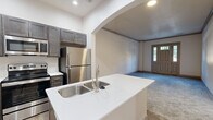 Located at 3006 Eden Ave in Cincinnati, OH, this 2-bedroom, 1-bathroom residence offers a thoughtfully designed single-floor layout. The modern kitchen is a standout feature, showcasing dark cabinetwood cabinetry, crisp white countertops, a center island with a stainless steel sink and dishwasher, and a full suite of stainless steel appliances including a range, microwave, and refrigerator. Wood-look flooring ties the kitchen together with a clean, contemporary aesthetic. The living area welcomes residents through a classic paneled entry door with transom windows, flooding the space with natural light. Soft, neutral carpet extends throughout the living and bedroom areas, creating a warm and comfortable atmosphere. The spacious primary bedroom features large windows with views of the surrounding greenery, enhancing the sense of openness. An arched entryway adds an architectural touch connecting the living and kitchen areas. The bathroom is clean and functional, offering a tub-shower combination, wood-look flooring, white countertops, and brushed nickel fixtures. A dedicated closet provides convenient storage, rounding out this efficiently organized and move-in-ready residence.