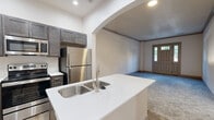 Located at 3006 Eden Ave in Cincinnati, OH, this 2-bedroom, 1-bathroom residence offers a thoughtfully designed single-floor layout. The modern kitchen is a standout feature, showcasing dark cabinetwood cabinetry, crisp white countertops, a center island with a stainless steel sink and dishwasher, and a full suite of stainless steel appliances including a range, microwave, and refrigerator. Wood-look flooring ties the kitchen together with a clean, contemporary aesthetic. The living area welcomes residents through a classic paneled entry door with transom windows, flooding the space with natural light. Soft, neutral carpet extends throughout the living and bedroom areas, creating a warm and comfortable atmosphere. The spacious primary bedroom features large windows with views of the surrounding greenery, enhancing the sense of openness. An arched entryway adds an architectural touch connecting the living and kitchen areas. The bathroom is clean and functional, offering a tub-shower combination, wood-look flooring, white countertops, and brushed nickel fixtures. A dedicated closet provides convenient storage, rounding out this efficiently organized and move-in-ready residence.