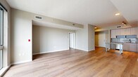 This well-appointed 2-bedroom, 1-bathroom residence at 880 Pacific Street in Stamford, CT offers a thoughtfully designed single-floor layout with a clean, contemporary aesthetic throughout. Light-toned hardwood-style flooring flows seamlessly across the entire space, lending warmth and visual continuity to every room.

The open-concept kitchen and living area serves as the heart of the home. The kitchen is outfitted with light wood cabinetry extending to the ceiling, a glass tile backsplash, stainless steel appliances including a gas range, microwave, dishwasher, and refrigerator, complemented by sleek countertops and a central island/table for casual dining or workspace.

The living area is generously proportioned, bathed in natural light from large floor-to-ceiling windows that frame views of the surrounding Stamford skyline and neighboring architecture. The spacious primary bedroom continues the bright, airy feel with its own oversized window wall, while the second bedroom offers a comfortable, versatile layout with warm neutral tones.

Two closets provide ample storage, including a walk-in style closet with wire shelving. The bathroom features a full soaking tub with white subway tile surround and hardwood-style flooring. A dedicated laundry area rounds out this efficient and modern residence.
