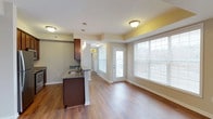 This well-designed 1-bedroom, 1-bathroom residence offers a thoughtfully planned single-floor layout that maximizes comfort and functionality. The open-concept living and dining area is bathed in natural light, courtesy of large windows dressed with blinds that overlook the outdoors. Warm hardwood-style flooring flows seamlessly throughout the main living spaces, adding a touch of elegance and cohesion to the interior.

The kitchen features rich, dark wood cabinetry and a granite-topped breakfast bar that serves as both a prep surface and casual dining space. A pendant light fixture above the bar adds a refined accent, while the layout allows for easy interaction between the kitchen and living area. The kitchen is equipped with a sink set into the countertop and provides ample storage within its cabinetry.

The living area is generously proportioned, offering flexible space for a variety of furniture arrangements. A glass-paneled entry door allows additional natural light to filter in, enhancing the bright and airy ambiance of the unit. Neutral wall tones and clean architectural lines contribute to a modern yet welcoming atmosphere throughout. The overall design reflects a practical, contemporary aesthetic well-suited for comfortable everyday living.