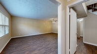 Located at 3370 Lansbury Village Dr in Atlanta, GA, this two-story home offers three bedrooms and five bathrooms thoughtfully distributed across two well-proportioned floors. The main level welcomes you through a dedicated entrance that flows into a bright, open living room featuring rich hardwood-style flooring, a ceiling fan with light fixture, and a row of windows that fill the space with natural light. The kitchen is outfitted with warm cherry wood cabinetry, granite-style countertops, a tile backsplash, and black appliances including a range, dishwasher, and refrigerator. A staircase connects the two levels, with multiple hallways providing seamless circulation throughout. The bedrooms are generously sized, with the primary bedroom offering its own dedicated closet space and private bathroom access. Additional bedrooms feature plush carpeting and walk-in closets with built-in shelving. The bathrooms are clean and functional, with select units showcasing rich wood vanities topped with stone counters and mirrored medicine cabinets, while others feature tub-shower combinations with white tile surrounds. Hardwood-style flooring runs through the main living areas, complemented by carpet in the bedrooms, creating a balanced and comfortable interior throughout this well-laid-out Atlanta home.