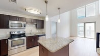 Located at 8250 Westpark Dr, Unit 740 in McLean, Virginia, this two-bedroom, two-bathroom residence spans two floors, offering a well-organized and functional layout. The main floor hosts the majority of the living space, including a thoughtfully designed kitchen featuring rich dark-wood cabinetry, stainless steel appliances — including a refrigerator, range, microwave, and dishwasher — a subway tile backsplash, granite countertops, and a central island with pendant lighting overhead. Light hardwood flooring runs throughout the kitchen and living areas, creating a warm, cohesive aesthetic. Both bathrooms are finished with granite-topped dark wood vanities, tile flooring, and tub-shower combinations. The bedrooms are carpeted in neutral tones and filled with natural light from large windows that overlook the surrounding community. The spacious primary bedroom includes convenient access to a closet and bathroom. A staircase with a dark-wood and white baluster railing leads to the upper level, where additional living space offers an open loft-style area with plush carpeting and a bright window. The clean, neutral palette throughout provides a versatile backdrop suited to a variety of interior styles.