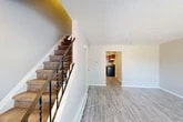 Located at 15 Galloway Dr in Liverpool, NY, this two-story home offers a practical and comfortable layout across two well-proportioned floors. The main level features a bright, open living room with light gray vinyl plank flooring and a textured ceiling, seamlessly connected to the kitchen via an arched passageway. The kitchen is equipped with warm-toned wood cabinetry, granite-style countertops, stainless steel appliances including a refrigerator and dishwasher, and a window that brings in natural light. A peninsula-style cabinet unit adds additional prep and storage space. A carpeted staircase with decorative wrought-iron railings leads to the upper level, where both bedrooms are located. The generously sized primary bedroom features plush carpeting, a textured ceiling, a window with outdoor views, and a closet. The second bedroom is similarly appointed with carpet, a closet, and neutral tones throughout. Each floor is served by its own bathroom; the bathrooms are clean and simply designed with white fixtures and mirrored medicine cabinets. Five closets throughout the home provide ample storage. The overall ambiance is neutral and move-in ready, with a straightforward, functional design well suited to everyday living.