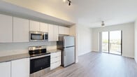 Located at 3300 Boutwell Rd in Lake Worth Beach, FL, this well-appointed 2-bedroom, 2-bathroom residence offers a thoughtfully designed single-floor layout with modern finishes throughout. The open-concept kitchen flows seamlessly into the living area, showcasing crisp white cabinetry extending to the ceiling, a subtle tile backsplash, light stone countertops, and a full suite of stainless steel appliances including a range, built-in microwave, dishwasher, and refrigerator. Light wood-style flooring runs through the main living areas, complementing the bright, neutral palette. The living space is equipped with a ceiling fan and opens to a private balcony through sliding glass doors, offering expansive outdoor views of the surrounding landscape. Both bedrooms feature plush carpet flooring and ceiling fans, with the primary bedroom offering a generous footprint and direct balcony access. The primary bathroom includes a dual-sink vanity with dark hardware accents, large-format tile flooring, and a separate shower. The second bathroom mirrors the clean aesthetic with a single vanity and tub-shower combination. A dedicated closet completes the functional layout of this contemporary residence.