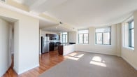Located on the 15th floor at 1212-28 Olive St in St. Louis, Missouri, this single-floor unit delivers a well-organized open layout with distinct living, kitchen, and private areas. The open-concept living and dining area features a combination of rich hardwood flooring and plush carpeting, with multiple large windows that frame expansive views of the St. Louis skyline and surrounding cityscape. Natural light flows generously throughout, accentuating the clean, neutral wall tones and white ceilings with structural beam detailing.

The kitchen is a functional centerpiece, outfitted with dark espresso cabinetry, stainless steel appliances including a refrigerator, range, and microwave, and a sleek island featuring dark granite countertops and an integrated sink. The kitchen transitions seamlessly into the main living space, reinforcing the open-plan design.

The bedrooms are carpeted and finished with neutral walls, offering a quiet retreat from the main living areas. The bathrooms feature large-format stone-look tile throughout, including in the walk-in glass-enclosed shower, and include dark-finished vanities with white countertops and chrome fixtures, contributing a polished, contemporary aesthetic throughout.