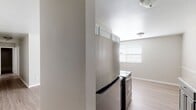 This single-story residence presents a clean, updated interior with a cohesive neutral color palette throughout. The kitchen serves as a functional centerpiece, featuring a galley-style layout with two-tone cabinetry — white upper cabinets paired with sage-green lower cabinets — complemented by granite-look countertops and stainless steel appliances, including a refrigerator and electric range. A window allows natural light to brighten the space.

Adjacent to the kitchen, the dining area offers an open, airy feel with light wood-look flooring that extends consistently throughout the unit. The living area is generously proportioned, with neutral taupe walls and white trim providing a versatile backdrop.

The bedrooms are well-sized, with one room featuring dual windows that bring in ample natural light. Both rooms offer light flooring and closet access, creating practical, comfortable spaces.

The bathroom includes a white vanity with an integrated sink, a large wall mirror, and easy access to the central hallway. The hallway connects all rooms efficiently, as illustrated by the 3D layout view, which reveals a straightforward, well-organized floor plan designed for comfortable everyday living.
