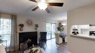 Located at 6100 Barrowood Dr in Raleigh, NC, this single-floor residence offers a thoughtfully designed layout that blends comfort and functionality. The living area serves as the heart of the home, showcasing rich hardwood flooring, a classic fireplace with a clean white mantle and dark surround, and a ceiling fan that adds both style and practicality. Natural light flows generously through large sliding glass doors that open directly onto a private balcony, offering a seamless connection to the outdoors and views of lush greenery beyond. Adjacent to the living space, the dining area features an elegant pendant light fixture and accommodates a round dining table, creating an inviting setting for meals and gatherings. The open flow between the living and dining areas enhances the sense of space throughout the home. A pass-through opening hints at a nearby kitchen, suggesting convenient access and an efficient layout. Neutral wall tones and consistent hardwood flooring throughout the shared spaces create a cohesive and welcoming ambiance. The overall design balances warm, residential character with clean, modern touches, making this Raleigh home a comfortable and well-appointed single-level retreat.
