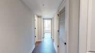 This contemporary single-floor residence showcases a thoughtfully designed open layout with a clean, modern aesthetic throughout. The kitchen serves as a visual centerpiece, featuring bold blue cabinetry that extends to the ceiling, white subway tile backsplash, quartz countertops, stainless steel appliances, and a large kitchen island with pendant lighting overhead — ideal for both cooking and casual entertaining. The kitchen flows seamlessly into the living area, which is bathed in natural light from oversized windows and offers direct access to a private balcony with open urban views.

Rich hardwood-style flooring runs consistently throughout the main living spaces and bedrooms, lending warmth and cohesion to the interior. The bedrooms are generously proportioned, with large windows that bring in abundant daylight and views of the surrounding cityscape. Ample closet storage is provided, including a set of classic double doors leading to a sizable closet.

The primary bathroom is finished with a wood-toned vanity, a frameless glass walk-in shower, and light tile flooring, delivering a clean and spa-like feel. A second full bathroom mirrors this refined style, offering a soaking tub and shower combination with white tile surround. The hallway connecting the rooms features louvered doors and a sprinkler system, reflecting thoughtful construction throughout.
