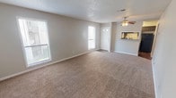 This 1-bedroom, 1-bathroom unit is thoughtfully laid out across a single floor, offering a comfortable and functional living environment. The living room serves as the central gathering space, featuring plush wall-to-wall carpeting, neutral gray walls, and a textured ceiling with a ceiling fan overhead. Multiple windows allow natural light to fill the room, creating a bright and welcoming atmosphere. A pass-through opening connects the living area directly to the kitchen, enhancing the open feel of the space.

The kitchen is equipped with dark cabinetry, granite-style countertops, a stainless steel sink, a subway tile backsplash, and black appliances including a full-size refrigerator. Hard surface flooring in the kitchen and bathroom provides a practical contrast to the carpeted living and bedroom areas.

The bedroom is generously sized, featuring the same neutral carpeting and a ceiling fan with a window that brings in natural light. The full bathroom includes a dark vanity with a granite-style countertop, a tiled tub-shower combination, and hardwood-style flooring, offering a clean and cohesive finish throughout.