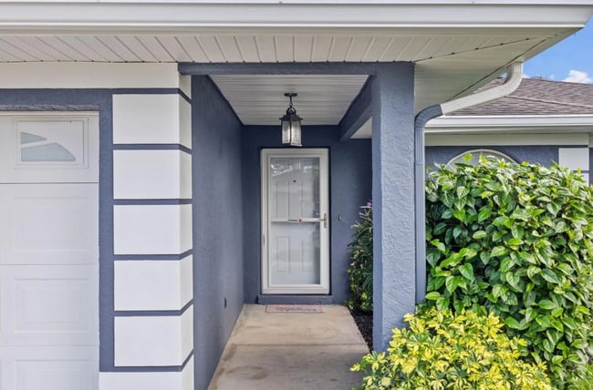 Cozy front porch entry with covered space and lush landscaping. - 1932 Brainerd Ct