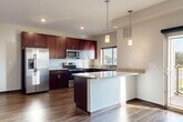 This contemporary 1-bedroom apartment offers 920 square feet of thoughtfully designed living space. The heart of the home is an open-concept living area, showcasing rich wood flooring that extends throughout, creating a warm and inviting atmosphere. The gourmet kitchen is a highlight, boasting rich cherry wood cabinetry, sleek granite countertops, and stainless steel appliances, including a side-by-side refrigerator and built-in microwave. 

The spacious bedroom, measuring 200 square feet, features plush carpeting and a generous walk-in closet, providing ample storage. The bathroom is elegantly appointed with a granite vanity top and a modern tub-shower combination. Large windows in both the living area and bedroom allow for abundant natural light and offer pleasant views of the surrounding area.

Additional features include a modern electric fireplace in the living room, recessed lighting, and a ceiling fan in the bedroom for added comfort. The unit's efficient layout maximizes space utilization, making it an ideal choice for comfortable urban living. Located at 360 @ Jordan West #2319 Cove, this apartment combines style, functionality, and a prime location.