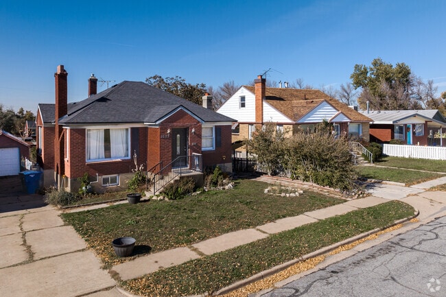 A charming red brick bungalow is neighbors to other brick bungalows of a similar style.