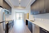 Located at 7480 Birdwood Ave in McLean, VA, this efficiently designed one-bedroom, one-bathroom residence offers a thoughtfully laid-out single-floor plan with a cohesive modern aesthetic. The galley-style kitchen is a standout feature, showcasing dark wood cabinetry with brushed nickel hardware, white quartz countertops, a subway tile backsplash, and a full suite of stainless steel appliances including a refrigerator, stove, built-in microwave, and dishwasher. Light wood-tone flooring runs throughout the kitchen and living areas, enhancing the bright, open feel. The combined dining and living area flows naturally from the kitchen toward a large window that fills the space with natural light and provides outdoor views. The bedroom features plush carpeting, tall windows that allow ample daylight, and a closet with sliding doors, creating a calm and comfortable retreat. The bathroom is finished with large-format floor tile, a white soaking tub with full subway tile surround, a dark wood vanity with a white countertop, and brushed nickel fixtures. Additional conveniences include in-unit laundry, two closets for storage, and a dedicated entrance. A tray ceiling detail in the kitchen adds an architectural touch to this clean, contemporary home.
