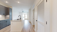 This well-appointed single-floor residence offers a smart, efficient layout that maximizes every inch of its living space. The open-concept design seamlessly connects the kitchen and living area, creating a welcoming and functional environment. The kitchen is a standout feature, showcasing gray shaker-style cabinetry, stainless steel appliances including a French door refrigerator, electric range, and built-in microwave, complemented by granite countertops, a white subway tile backsplash, and a central island with an undermount sink and matte black faucet. Light hardwood-style flooring flows continuously throughout the unit, enhancing the bright and airy ambiance created by recessed lighting and natural light from large windows. The living area benefits from a ceiling fan and direct access through glass-paneled French doors. The bedroom is a comfortable retreat, equipped with its own ceiling fan and access to a dedicated closet. The bathroom features a granite-topped vanity with gray cabinetry, a large framed mirror, and modern light fixtures. A louvered closet door adds a charming architectural detail to the hallway. Clean white walls and consistent matte black hardware tie the modern aesthetic together throughout the entire space.