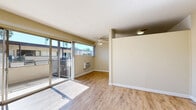 Located at 6717 Wilkinson Ave in North Hollywood, Los Angeles, this one-bedroom, one-bathroom unit offers a thoughtfully organized layout across a single floor. The open-concept living and dining area is bright and welcoming, featuring light-toned hardwood-style flooring, neutral warm beige walls, and a ceiling fan overhead. Large sliding glass doors flood the space with natural light and open directly onto a private balcony, offering views of the surrounding neighborhood framed by tall palm trees. A wall-unit air conditioner provides climate control in both the living area and bedroom. The kitchen is positioned conveniently adjacent to the dining space. The spacious bedroom is carpeted for comfort and includes a mirrored sliding-door closet that adds a sense of depth and light. Windows on two sides allow for cross-ventilation and natural brightness. The bathroom features tile flooring, white cabinetry, a granite-style countertop, and a well-lit vanity mirror. A dedicated closet provides additional storage. The overall aesthetic is clean and neutral, creating a versatile canvas well-suited to a variety of styles. The building exterior showcases a classic mid-century California architectural character, with open-air corridors and lush palm trees set against a sunny Los Angeles backdrop.