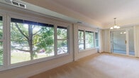 Located at 2223-1/2 Rogene Dr, this single-floor residence offers a well-planned layout with a variety of thoughtfully appointed spaces. The main living area is generously sized, featuring plush wall-to-wall carpeting, crown molding, and a bank of large windows dressed with flowing drape panels that frame picturesque views of mature, leafy trees. Natural light pours in throughout, creating a bright and welcoming atmosphere.

Several rooms showcase classic parquet wood flooring in a warm honey tone, adding character and visual interest. These rooms are served by ceiling light fixtures with pull-chain controls and benefit from windows overlooking the surrounding greenery. Multiple closets with bifold doors provide ample built-in storage within the bedroom areas.

The kitchen is equipped with warm oak cabinetry, generous counter space, an under-cabinet light fixture, a white double sink, and a dishwasher. Terracotta-style tile flooring anchors the space, and a doorway connects directly to an adjacent utility or laundry area.

The bathroom features clean white tile flooring, a full tub-shower combination, a vanity with white cabinetry, and a toilet — all finished in a crisp, bright palette. A carpeted hallway connects the bathroom to the parquet-floored rooms, maintaining a cohesive flow throughout the home. An additional exterior storage area with a concrete floor and lap-siding walls rounds out the property.
